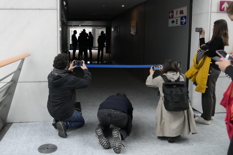 People take images as security officers gather in a corridor during a search the office of German MEP Maximilian Krah at the European Parliament in Brussels, Tuesday May, 7, 2024. Germany's top prosecutor's office says that authorities are searching the European parliament office of Maximilian Krah, the Alternative for Germany party's top candidate in the upcoming European Parliament elections. Krah, has been under scrutiny after an assistant of his was arrested last month on suspicion of spying for China. (AP Photo/Virginia Mayo)