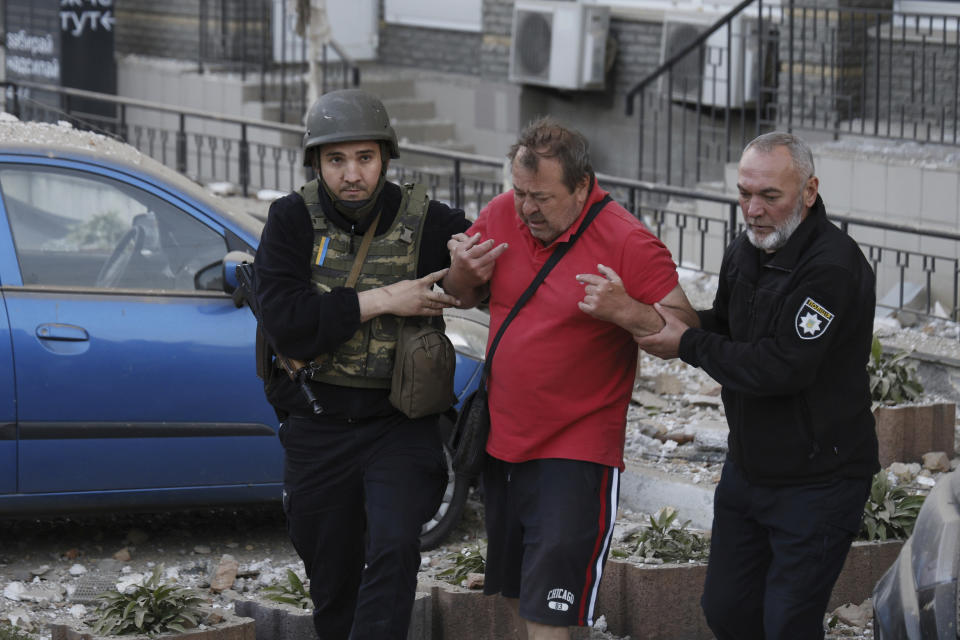 Agentes de policía ayudan a un hombre herido a salir de un edificio residencial y dirigirse a una ambulancia durante una ola de bombardeos en Kiev, Ucrania, el 30 de mayo de 2023. (AP Foto/Alex Babenko)