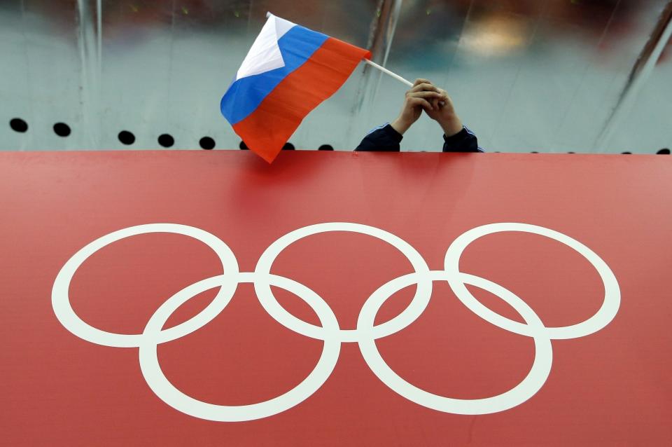 A Russian flag is held above the Olympic Rings at Adler Arena Skating Center during the Winter Olympics in Sochi, Russia on Feb. 18, 2014.