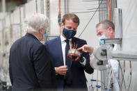 French President Emmanuel Macron, center, wearing a protective face mask, visits a factory of manufacturer Valeo in Etaples, , northern France, Tuesday May 26, 2020. Emmanuel Macron announced a 8 billion euro ($8.8 billion) plan Tuesday to save the country's car industry from huge losses wrought by virus lockdowns, including a big boost for electric vehicles. The plan includes government subsidies for car buyers and longer-term investment in innovative technology, especially in battery-powered cars. (Ludovic Marin, Pool via AP)