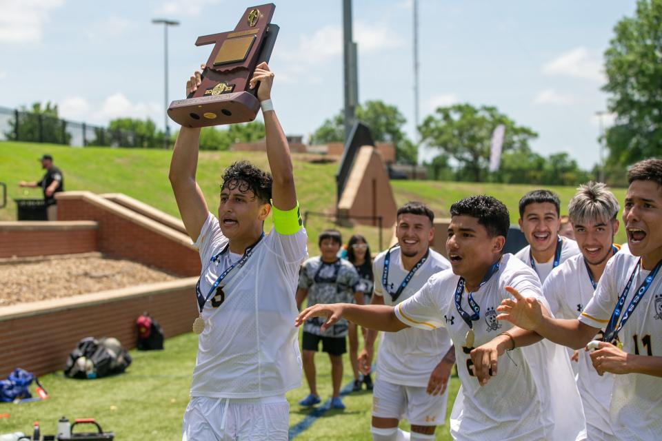 Santa Fe South's Jaire Estrada (6) carries the Class 5A boys state championship soccer trophy after Santa Fe South defeated East Central 2-0 at Rogers State University on Saturday, May 13, 2023, in Claremore. 