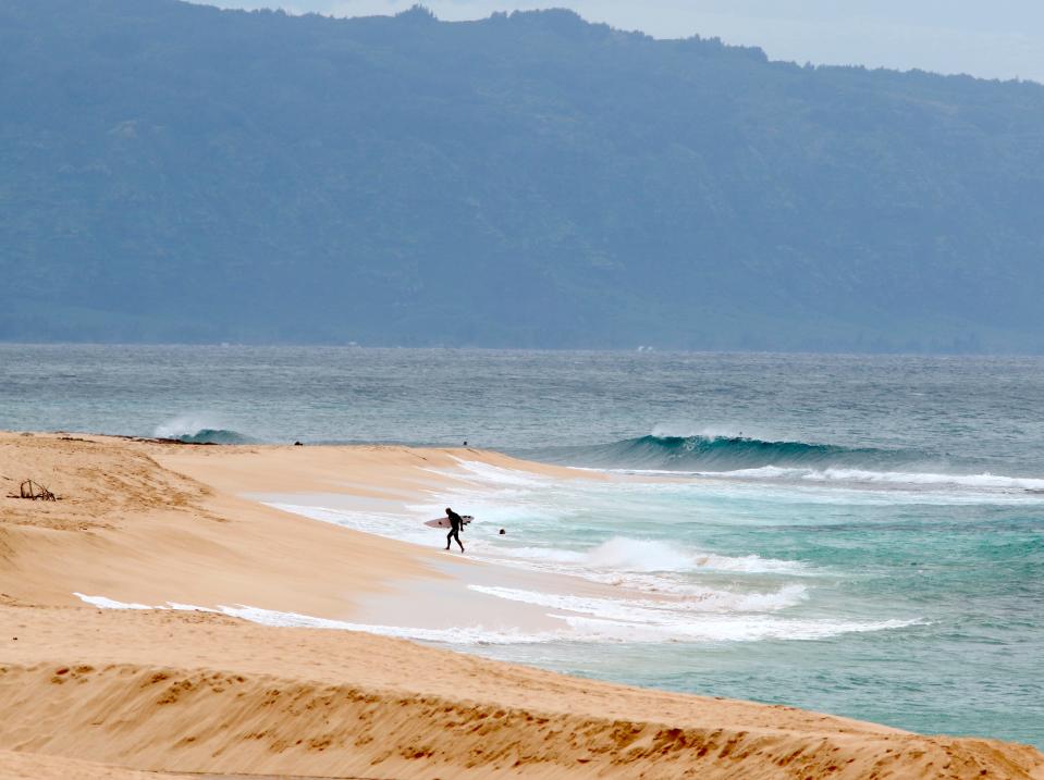 In this March 31, 2020 file photo a surfer walks out of the ocean on Oahu's North Shore near Haleiwa, Hawaii. Two free divers were found dead near Oahu's North Shore on July 23, 2023.