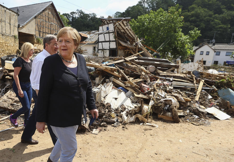 German Chancellor Angela Merkel, center, informs herself in the district of Iversheim about the situation in the flood-affected area and meet victims of the flood disaster Tuesday, July 20, 2021. (Wolfgang Rattay/Pool Photo via AP)