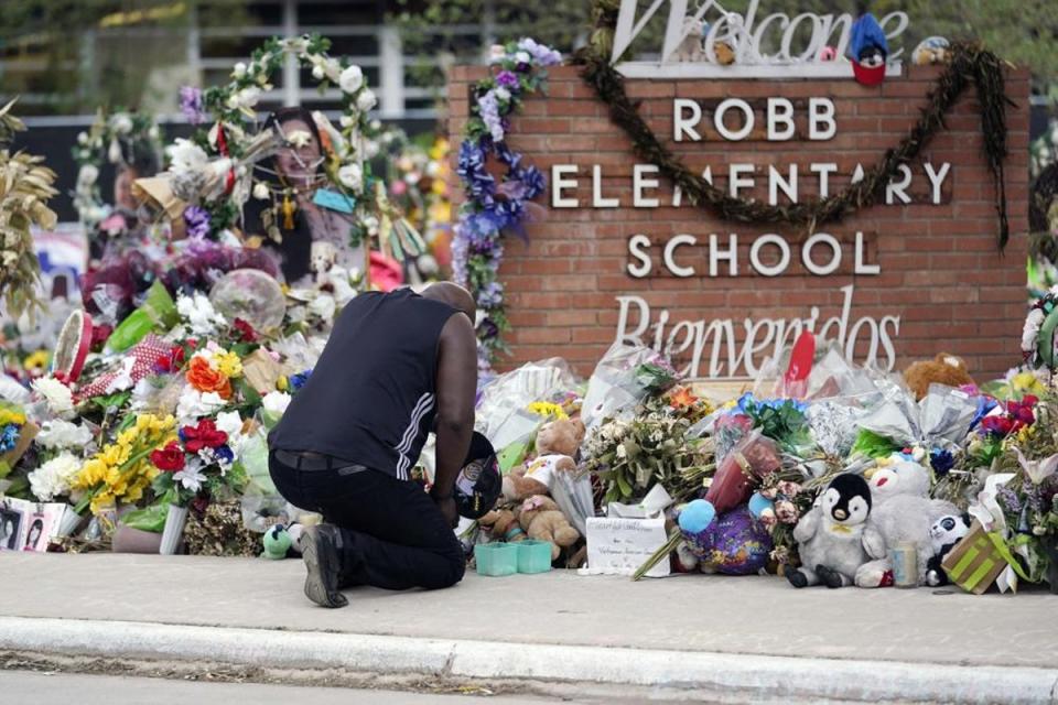 Un doliente presenta sus respetos en un monumento conmemorativo frente a la escuela primaria Robb (Associated Press)