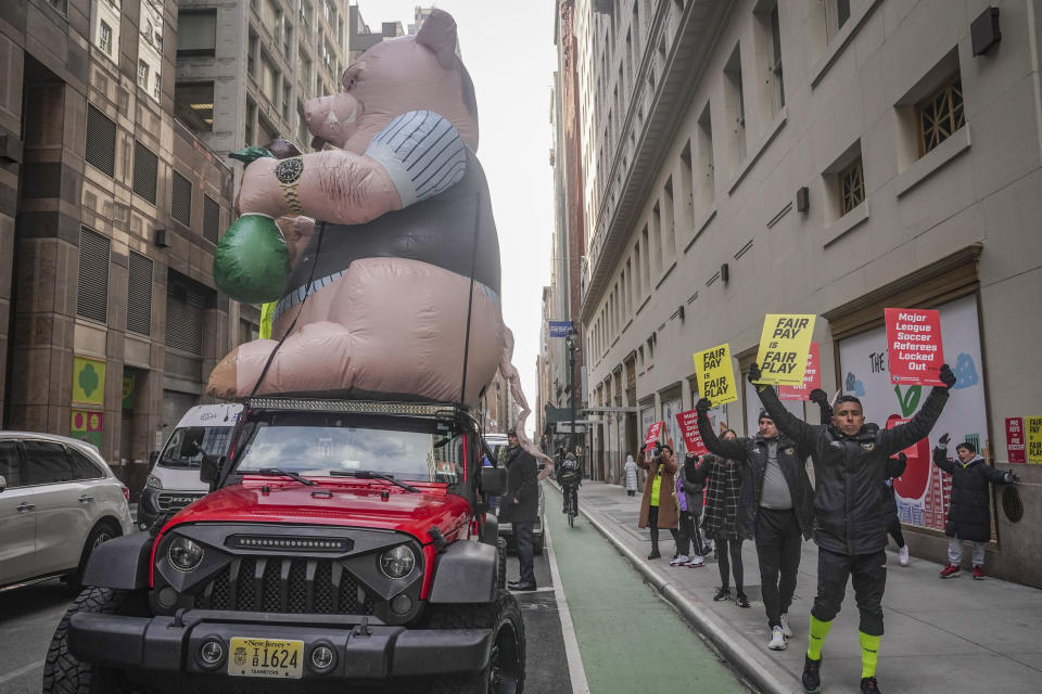 Major League Soccer (MLS) referees and supporters picket outside MLS headquarters around labor's symbolic "Greedy Pig" balloon, after MLS implemented a lockout against referees following their rejection of a contract offer, Wednesday, Feb. 21, 2024, in New York. (AP Photo/Bebeto Matthews)