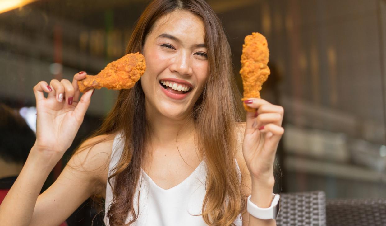 close up young asian woman holding fried chicken with happy feeling at outside restaurant for special day concept