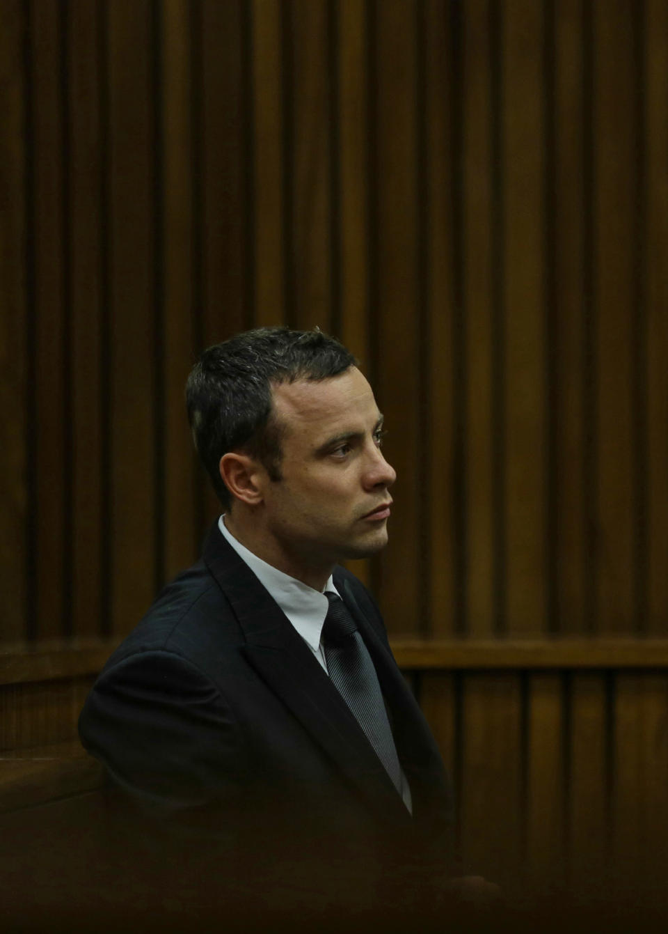 Oscar Pistorius sits in the dock and listens to cross questioning about the events surrounding the shooting death of his girlfriend Reeva Steenkamp, in court during his trial in Pretoria, South Africa, Tuesday, March 11, 2014. Pistorius is charged with the shooting death of Steenkamp, on Valentines Day in 2013. (AP Photo/Kevin Sutherland, Pool)