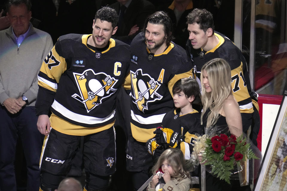 Pittsburgh Penguins' Kris Letang, center, poses for a photo with Sidney Crosby, Evgeni Malkin and his wife Catherine Laflamme, front right, son Alexander, and daughter Victoria, during a pre-game celebration of his 1000th NHL game played as a Pittsburgh Penguins defenseman before an NHL hockey game against the Philadelphia Flyers in Pittsburgh, Sunday, April 2, 2023. (AP Photo/Gene J. Puskar)