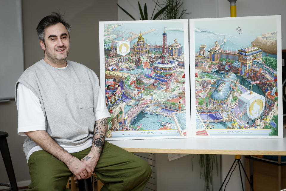 CORRECTS SPELLING OF FIRST NAME FROM HUGO TO UGO - French artist Ugo Gattoni poses next to the Paris 2024 Olympic and Paralympic posters at his workshop, in Ivry-sur-Seine, outside Paris, Tuesday Feb. 20, 2024. Vibrant colors and striking landmarks illuminate posters for the Paris Olympic Games in an Art Deco style inspired by the city's flamboyant past. The posters have been unveiled at the Musée d'Orsay. (AP Photo/Thomas Padilla)