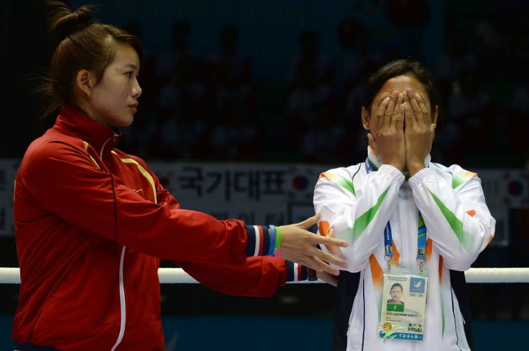 India's Sarita Devi is distraught on the 2014 Asian Games medal podium after refusing her bronze medal as Vietnam's Luu Thi Duyen tries touchingly to console her