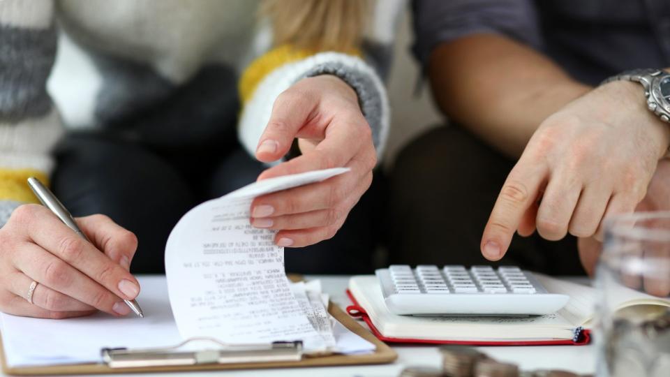 Close-up view of man and woman making account of family income.