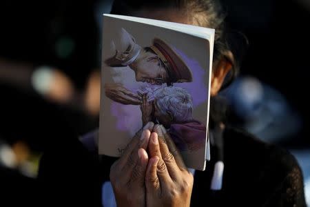 A woman prays as she holds a portrait of Thailand's late King Bhumibol Adulyadej before a procession to transfer his royal relics and ashes from the crematorium to the Grand Palace in Bangkok, Thailand, October 27, 2017. REUTERS/Athit Perawongmetha NO RESALES. NO ARCHIVES.