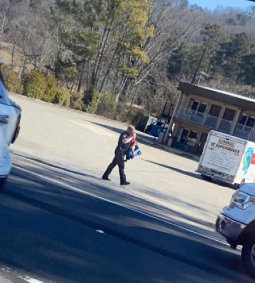 This photo taken Friday by passerby Conner Paulson shows Gadsden Police Lt. Josh Russell rescuing a child who had ventured onto Rainbow Drive in a toy car.