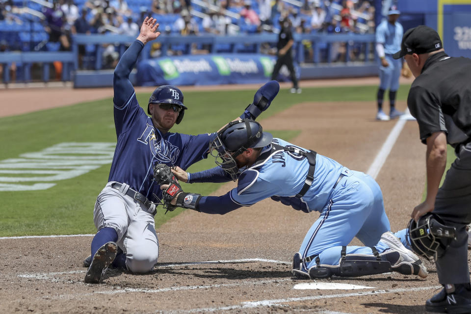 Toronto Blue Jays catcher Danny Jansen tags out Tampa Bay Rays' Mike Brosseau as home plate umpire Jansen Visconti watches during the fourth inning of a baseball game Sunday, May 23, 2021, in Dunedin, Fla. (AP Photo/Mike Carlson)