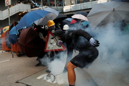 An anti-government protester tries to hit back a tear gas canister at riot police with his badminton racket, during a demonstration at Admiralty district in Hong Kong