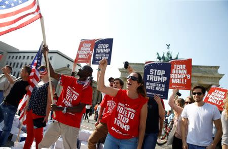 Campaigners pose with 'Stop Trump' signs in front of the Brandenburg Gate to urge Americans living abroad to register and vote in Berlin, Germany, September 23, 2016. REUTERS/Axel Schmidt