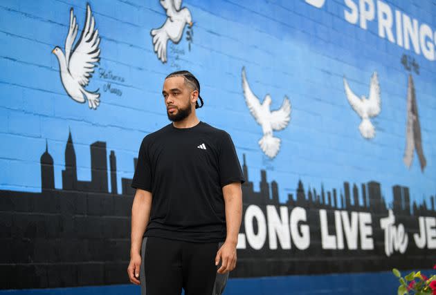 Local Buffalo activist Myles Carter stands in front of a memorial wall dedicated to the victims of the Tops supermarket massacre, located across the street from the supermarket.