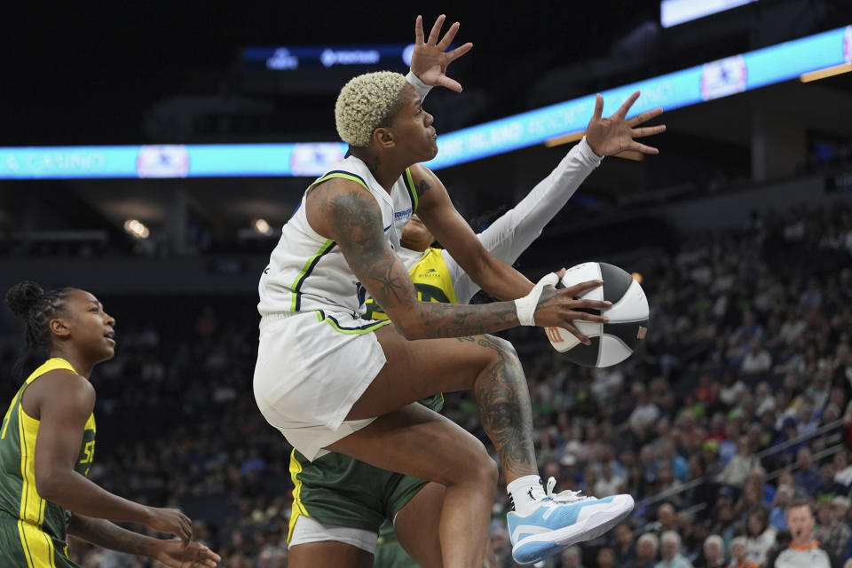 Minnesota Lynx guard Courtney Williams, front, goes up for a shot as Seattle Storm guard Victoria Vivians, back, defends during the first half of a WNBA basketball game, Sunday, June 9, 2024, in Minneapolis. (AP Photo/Abbie Parr)