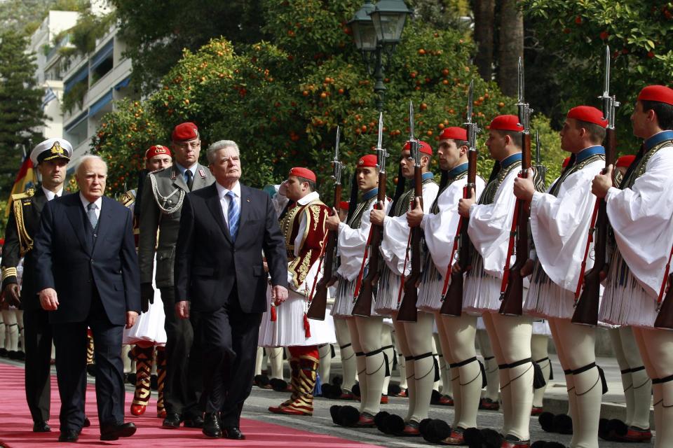 Greek President Karolos Papoulias, left, and his German counterpart Joachim Gauck, right, inspect a presidential guard during an official welcome ceremony outside the presidential palace, in Athens , on Thursday, March 6, 2014. Gauck is on a visit that will seek to lay to rest some of the ghosts of a brutal Nazi occupation, amid renewed anti-German sentiment stoked by Greece's financial crisis. His three-day visit will include a speech Friday at a site where German army troops massacred 92 villagers near the northeastern town of Ioannina, and a meeting with the town's Jewish community. (AP Photo/Kostas Tsironis)