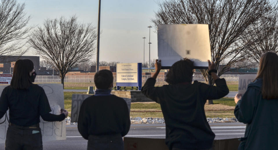 Protesters hold up signs on Prairieton Road across from the Federal Execution Chamber, Thursday, Dec. 10, 2020 in Terre Haute, Ind. The execution Brandon Bernard, convicted in the 1999 killing of two youth ministers in Texas is scheduled Thursday at the federal prison in Terre Haute, Indiana.. (Austen Leake/The Tribune-Star via AP)