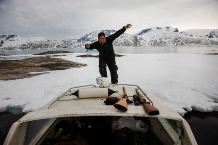 Seal hunter Henrik Josvasson jumps back onto his boat after searching for puffin eggs near the town of Tasiilaq, Greenland, June 16, 2018. REUTERS/Lucas Jackson