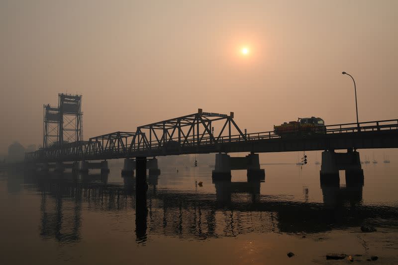 An RFS tanker passes over the smoke shrouded bridge at Batemans Bay, New South Wales, Australia