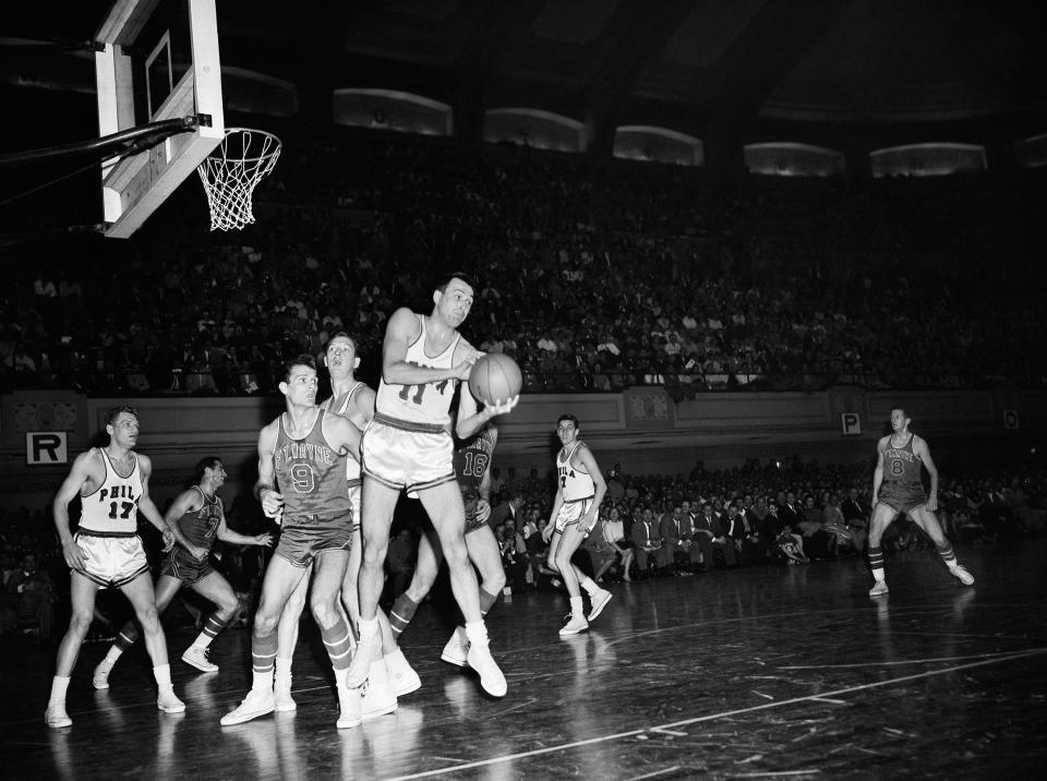 Paul Arizin (11) of the Philadelphia Warriors grabs a rebound as Mel Hutchins (9) of the Fort Wayne Pistons looks on on April 8, 1956. Others are (from left): Warrior Neil Johnston is behind Hutchins.