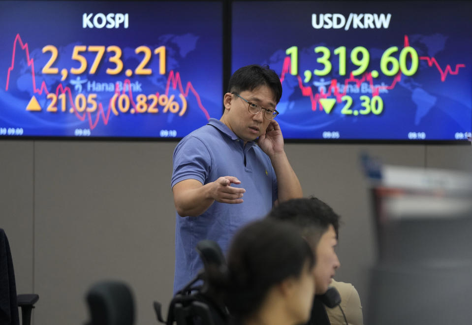 A currency trader gestures near the screens showing the Korea Composite Stock Price Index (KOSPI), top left, and the foreign exchange rate between U.S. dollar and South Korean won at the foreign exchange dealing room of the KEB Hana Bank headquarters in Seoul, South Korea, Wednesday, Aug. 30, 2023. Asian shares rose Wednesday, boosted by a Wall Street rally that came on positive reports on consumer confidence and job openings.(AP Photo/Ahn Young-joon)