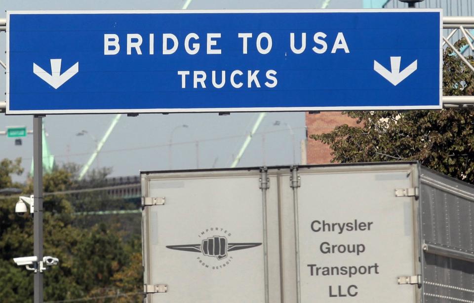 A commercial automotive supplier truck passes under a sign leading to the Ambassador bridge crossing over to Detroit, Michigan from Windsor, Ontario