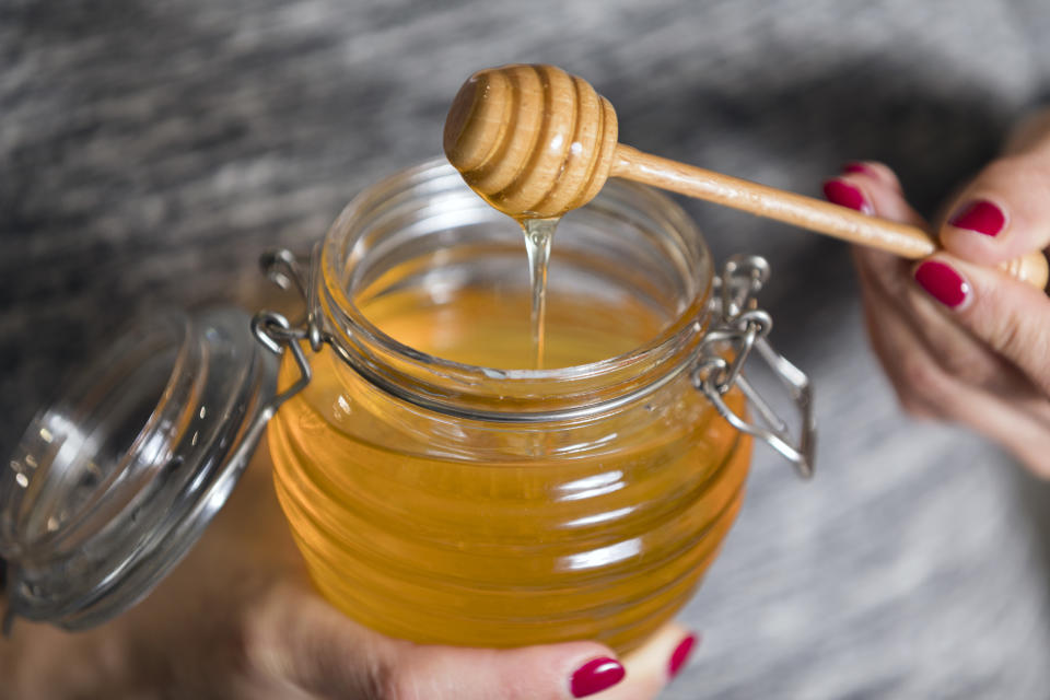 Woman hand holding glass jar of honey