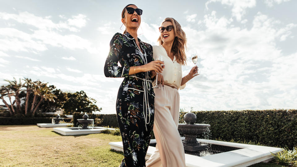 Portrait of two female friends walking on the lawn and laughing.