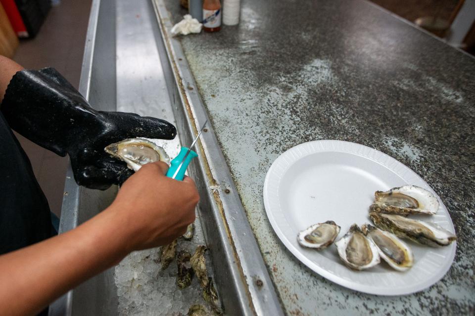 An employee of Shell Oyster Bar peels a plate of oysters on Wednesday, May 29, 2024.