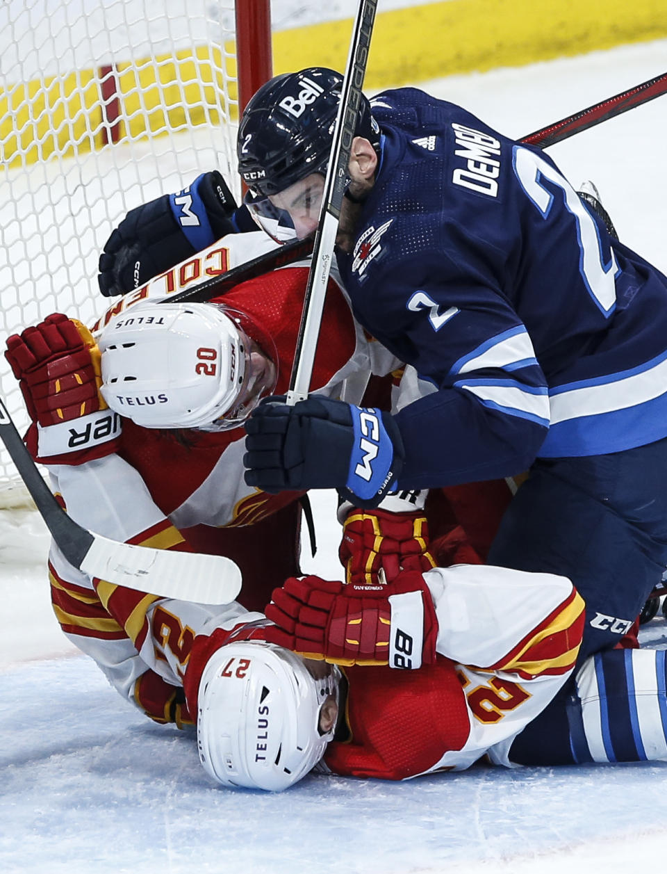 Winnipeg Jets' Dylan DeMelo (2) defends against Calgary Flames' Blake Coleman (20) and Matt Coronato (27) during the second period of an NHL hockey game Thursday, April 4, 2024, in Winnipeg, Manitoba. (John Woods/The Canadian Press via AP)