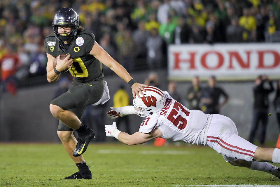 Oregon quarterback Justin Herbert runs for a touchdown past Wisconsin linebacker Jack Sanborn during second half of the Rose Bowl NCAA college football game Wednesday, Jan. 1, 2020, in Pasadena, Calif. (AP Photo/Mark J. Terrill)