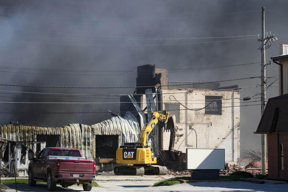 Workers knock down a section of site of an industrial fire the area as smoke billows from the site in Richmond, Ind., Wednesday, April 12, 2023. Authorities urged people to evacuate if they live near the fire. The former factory site was used to store plastics and other materials for recycling or resale. (AP Photo/Michael Conroy)