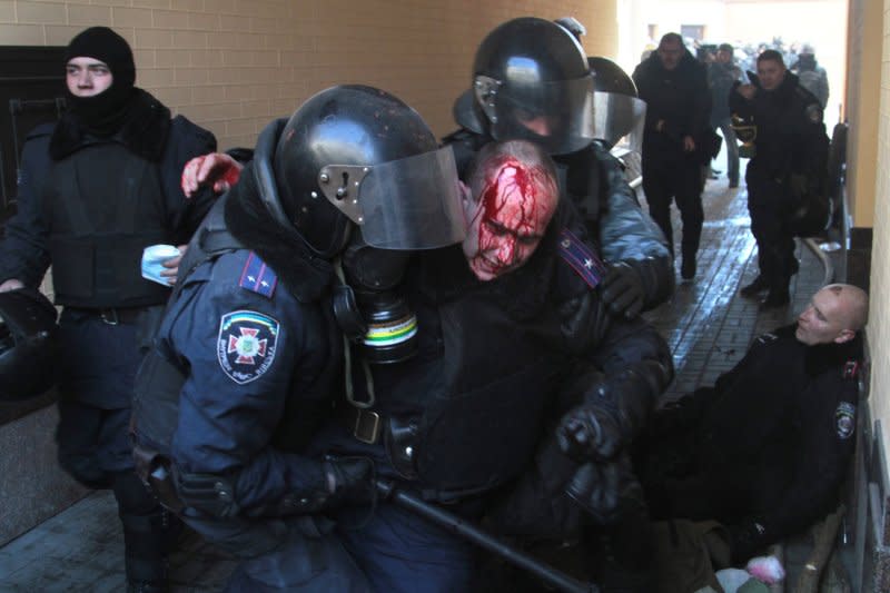 Ukrainian riot police help an injured officer during a clash with anti-government protesters outside the Parliament building in Kiev on February 18, 2014. File Photo by Sergey Starostenko/UPI