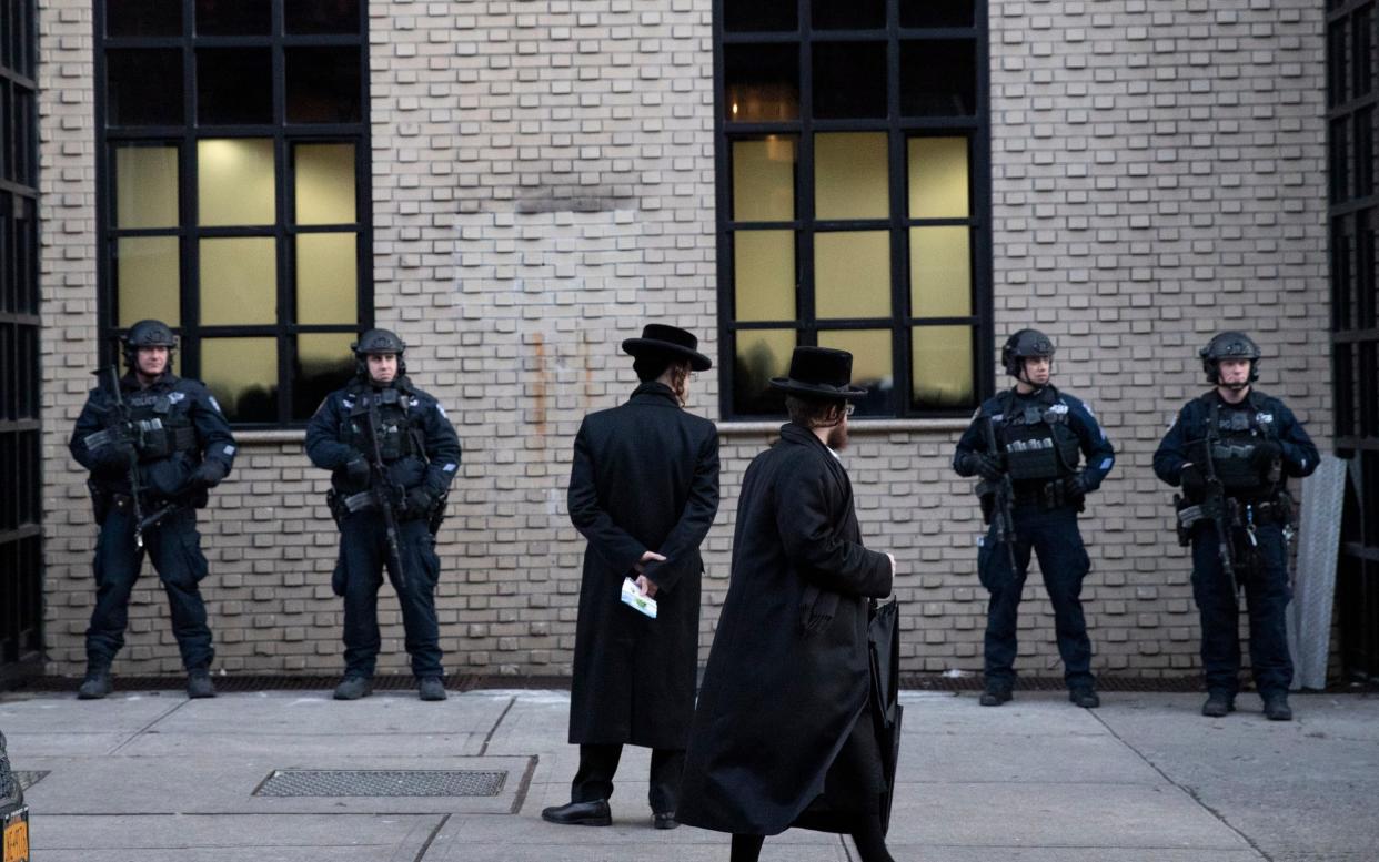 Orthodox Jewish men pass New York City police guarding a Brooklyn synagogue - AP