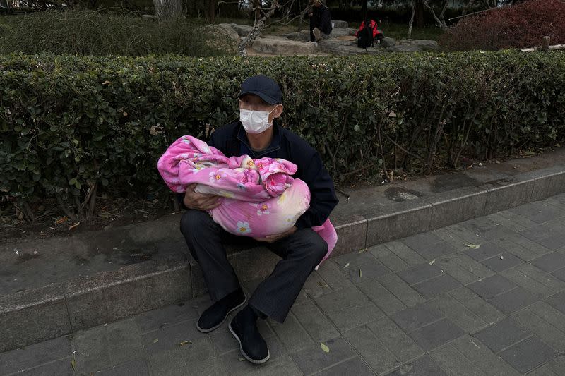 Man carrying a child sits outside a children's hospital in Beijing