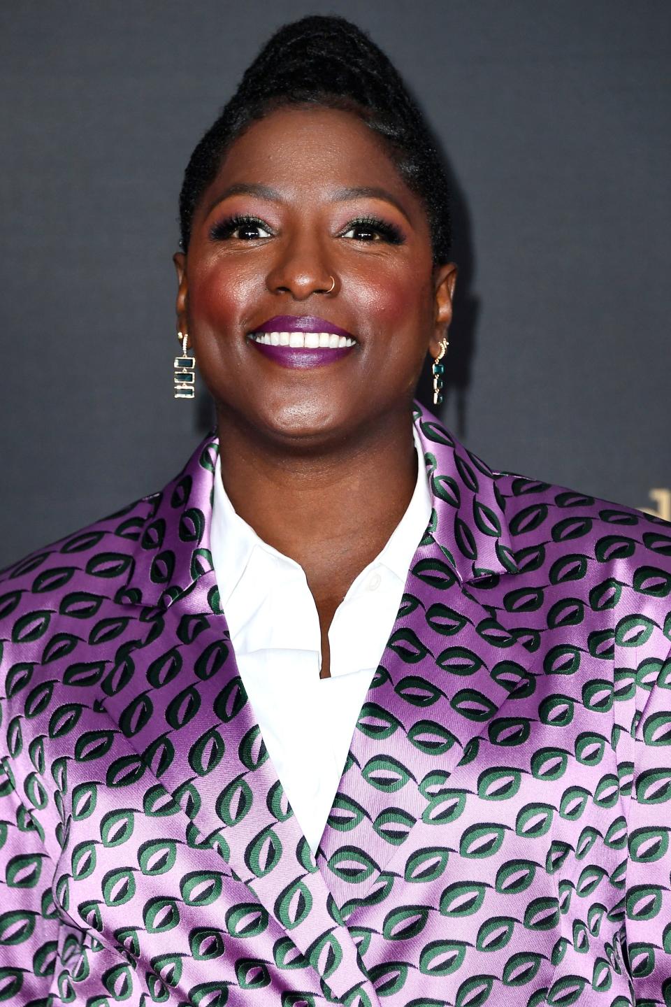 Rutina in a patterned blazer and white shirt smiling at a media event