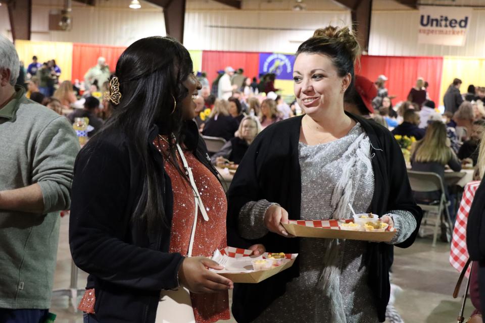 Ashli Andrews and Amanda Weatherford fill their trays with samples of mac and cheese at the Hope and Healing Place's annual The Big Cheese macaroni and cheese competition at the Rex Baxter Building Friday evening.