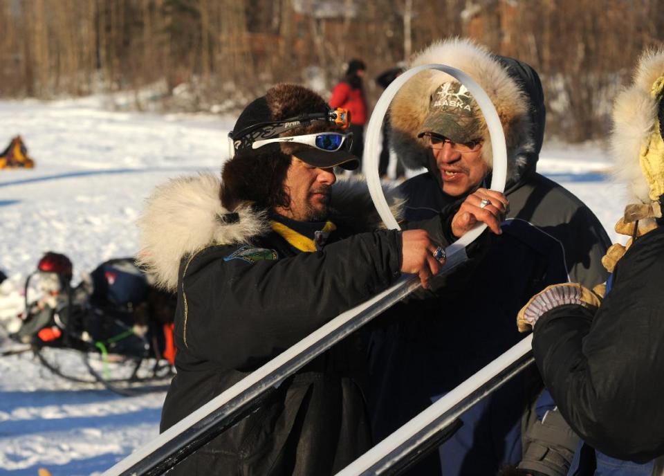 Iditarod musher Hugh Neff, from Tok, AK, changes the plastic on his runners as he talks with race judge Curtis Erhart at the Galena checkpoint during the 2014 Iditarod Trail Sled Dog Race on Friday, March 7, 2014. (AP Photo/The Anchorage Daily News Bob Hallinen)