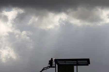 FILE PHOTO: A construction worker welds under stormy clouds high atop a structure being built by the U.S. Government next to the Mexican border in San Diego, California, U.S., December 1, 2018. REUTERS/Mike Blake