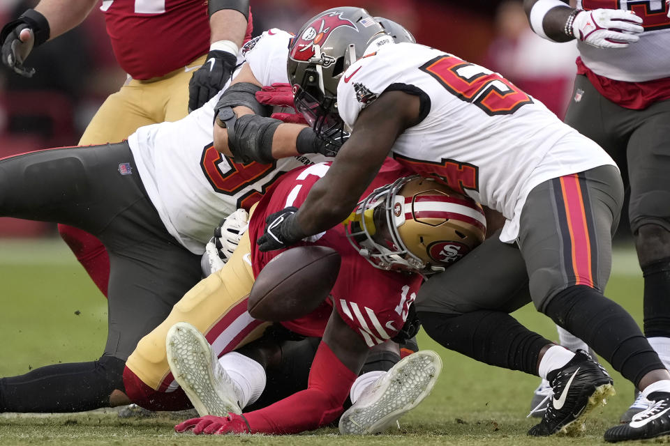 San Francisco 49ers wide receiver Deebo Samuel, middle, fumbles the ball while tackled between Tampa Bay Buccaneers linebacker Anthony Nelson, left, defensive tackle Rakeem Nunez-Roches, rear, and linebacker Lavonte David during the first half of an NFL football game in Santa Clara, Calif., Sunday, Dec. 11, 2022. The Buccaneers recovered the fumble. Samuel left the game after the play. (AP Photo/Tony Avelar)