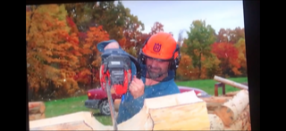Randy Woloszyn using a chainsaw while building a log cabin home.