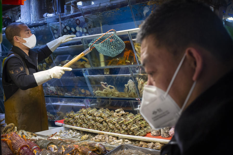 A customer wears a face mask as he shops for seafood at a market in Beijing, Saturday, March 14, 2020. The United States declared a state of emergency Friday as many European countries went on a war footing amid mounting deaths as the world mobilized to fight the widening coronavirus pandemic. For most people, the new coronavirus causes only mild or moderate symptoms, such as fever and cough. For some, especially older adults and people with existing health problems, it can cause more severe illness, including pneumonia. (AP Photo/Mark Schiefelbein)