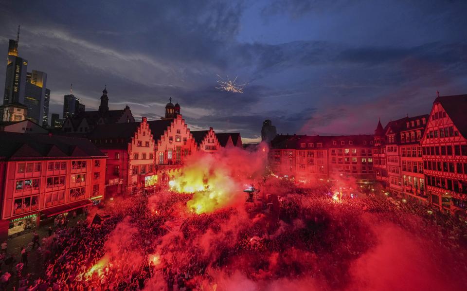 The supporters of the German Bundesliga soccer team of Eintracht Frankfurt light fireworks as they celebrate the arrival of the team for a welcome event in Frankfurt, Germany, Thursday, May 19, 2022 the day after Eintracht Frankfurt won the Europa League final match against Scottish team Glasgow Rangers FC in Seville.(AP Photo/Michael Probst)