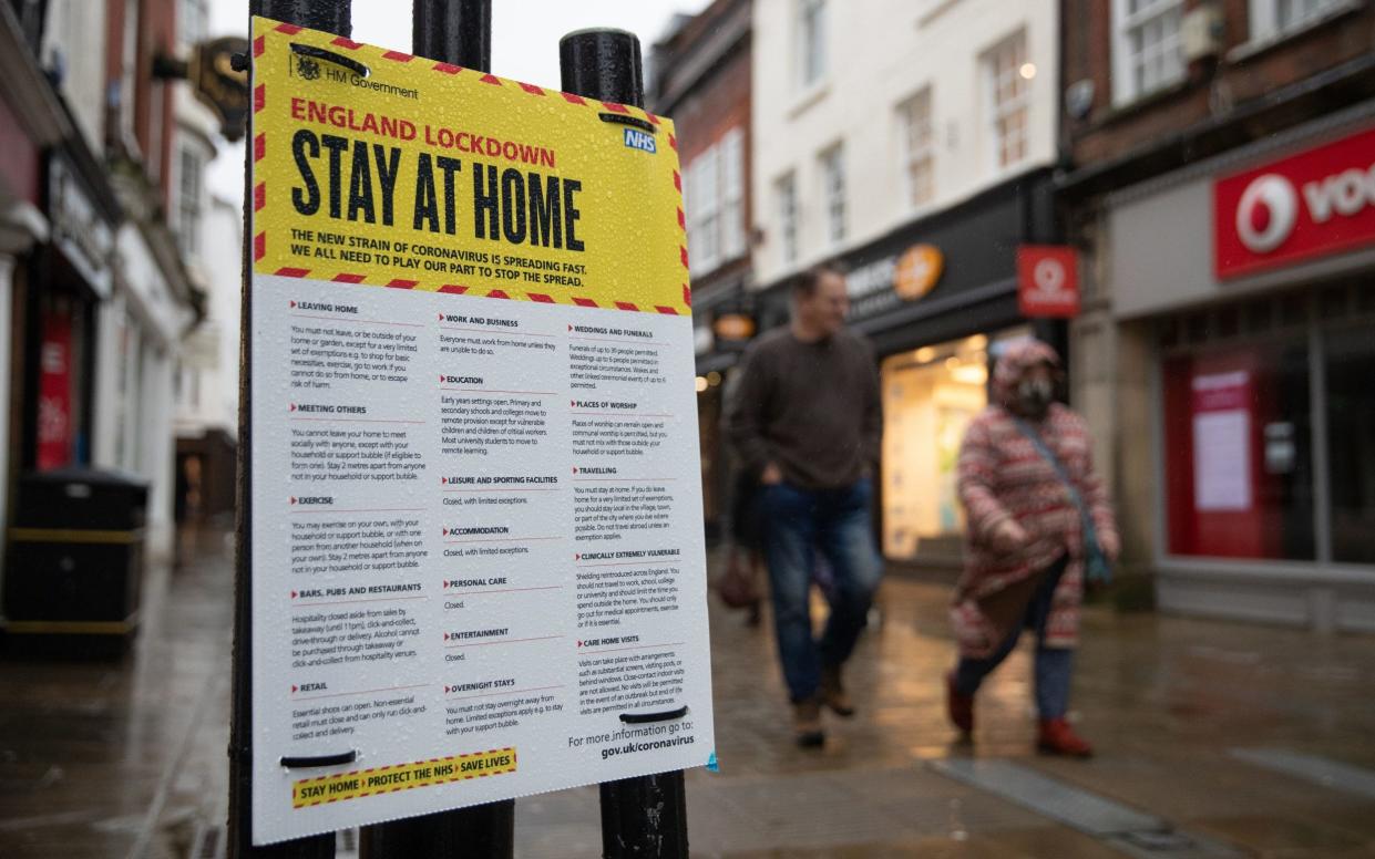 Pedestrians in Winchester, Hampshire, walk past a sign warning people to stay at home in the third coronavirus lockdown - Andrew Matthews/PA Wire