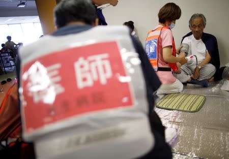 Evacuees receive medical health check by a doctor and another medical staff members at Mabi Clean Center, acting as an evacuation center, in Kurashiki, Okayama Prefecture, Japan, July 13, 2018. REUTERS/Issei Kato