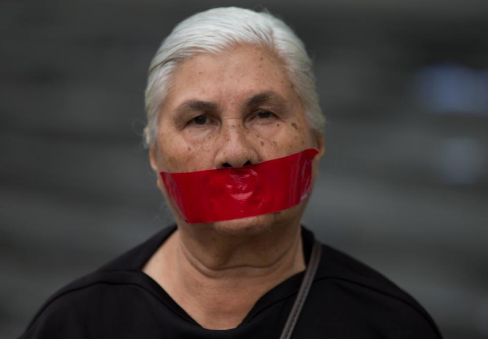 A woman with tape over her mouth in protest of officials breaking up protesters' camps, stands outside the United Nations headquarters in Caracas, Venezuela, Thursday, May 8, 2014. Hundreds of security forces broke up four camps maintained by student protesters, arresting 243 people in a Thursday pre-dawn raid. The camps consisting of small tents were installed more than a month ago in front of the UN building and other anti-government strongholds in the capital to protest against President Nicolas Maduro's government. (AP Photo/Fernando Llano)