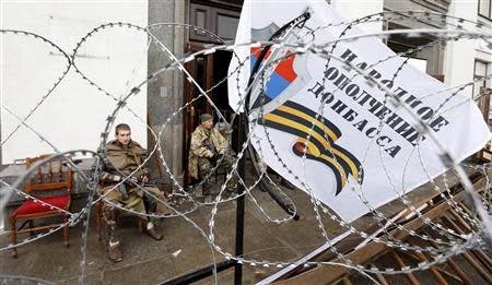 Pro-Russian armed men sit at the entrance to the regional government headquarters in Luhansk, eastern Ukraine, April 30, 2014. REUTERS/Vasily Fedosenko